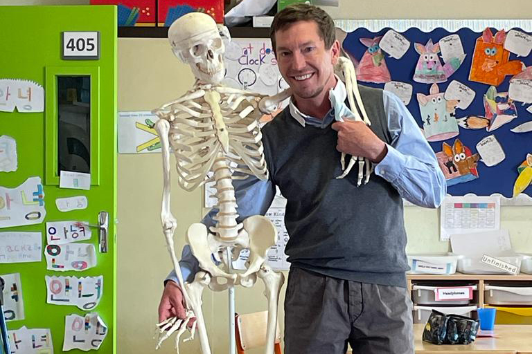 teacher holding a skeleton with its arm around his neck