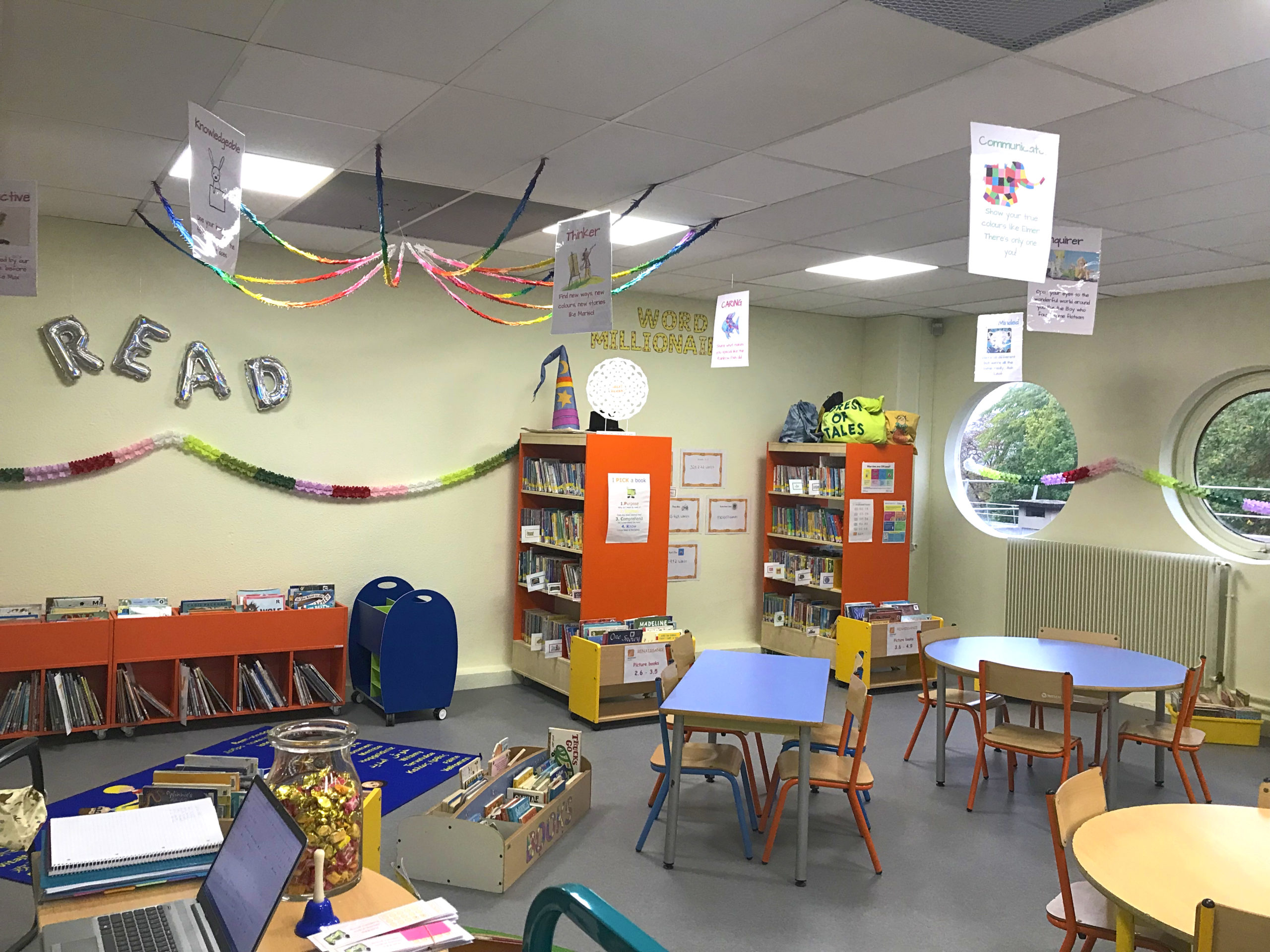 a decorated library with stocked shelves, tables and chairs