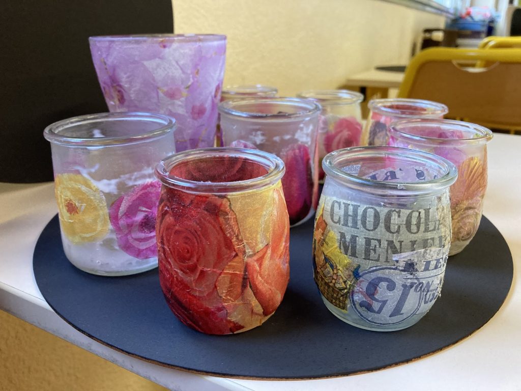 several glass candle holders made from yogurt jars and decorated with coloured paper