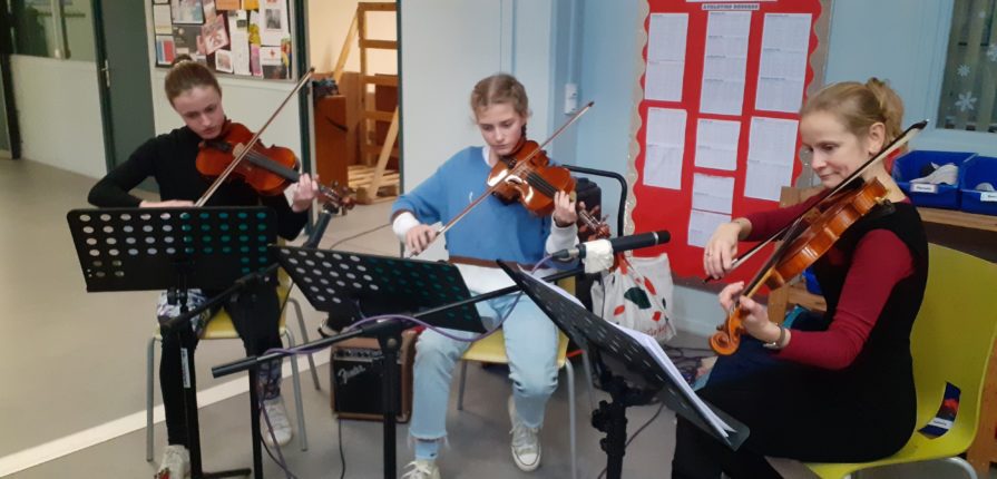 2 students and a teacher playing violins