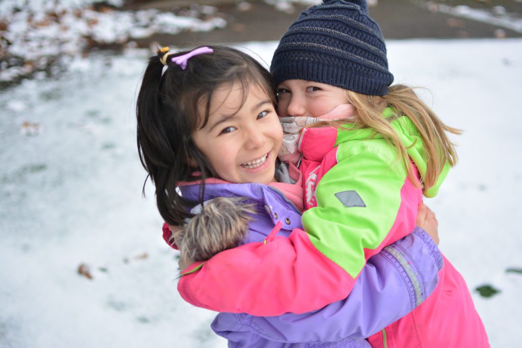 2 kindergarten students playing in the snow on the artificial pitch at the International School of Lyon’s English and French Kindergarten