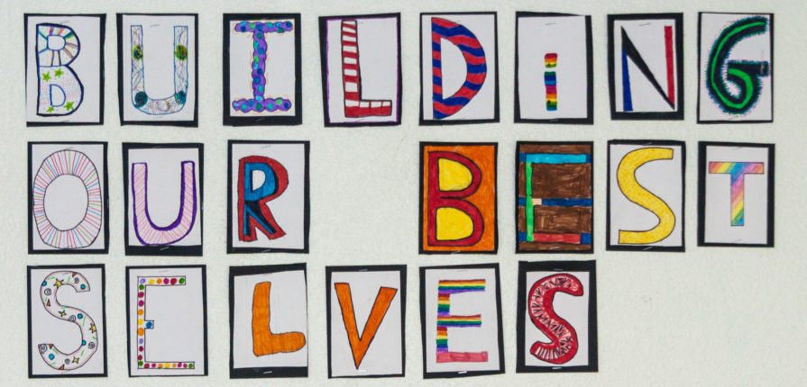 A student-made sign with the ISL school vision: "Building our Best Selves"