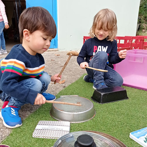 2 students hitting pans with sticks to make music