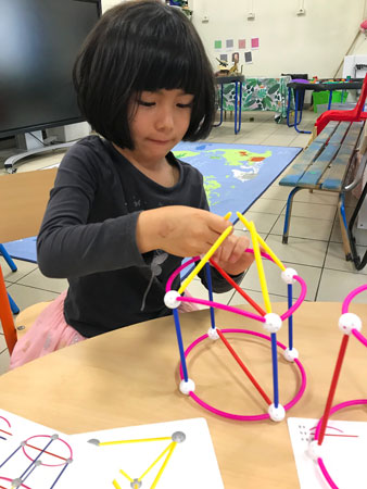 A student making 3D shapes with straws and connectors