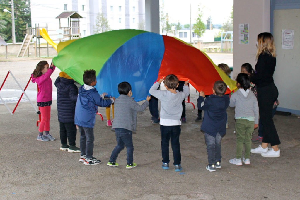 kindergarten students playing with a parachute