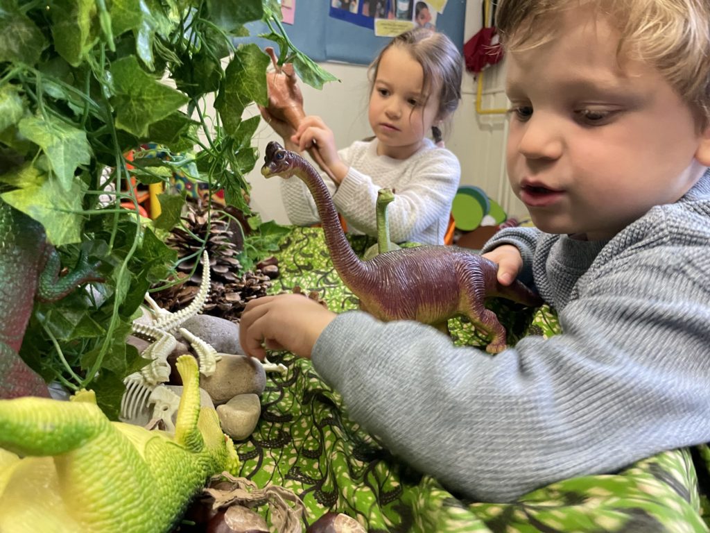 2 students playing with dinosaur toys