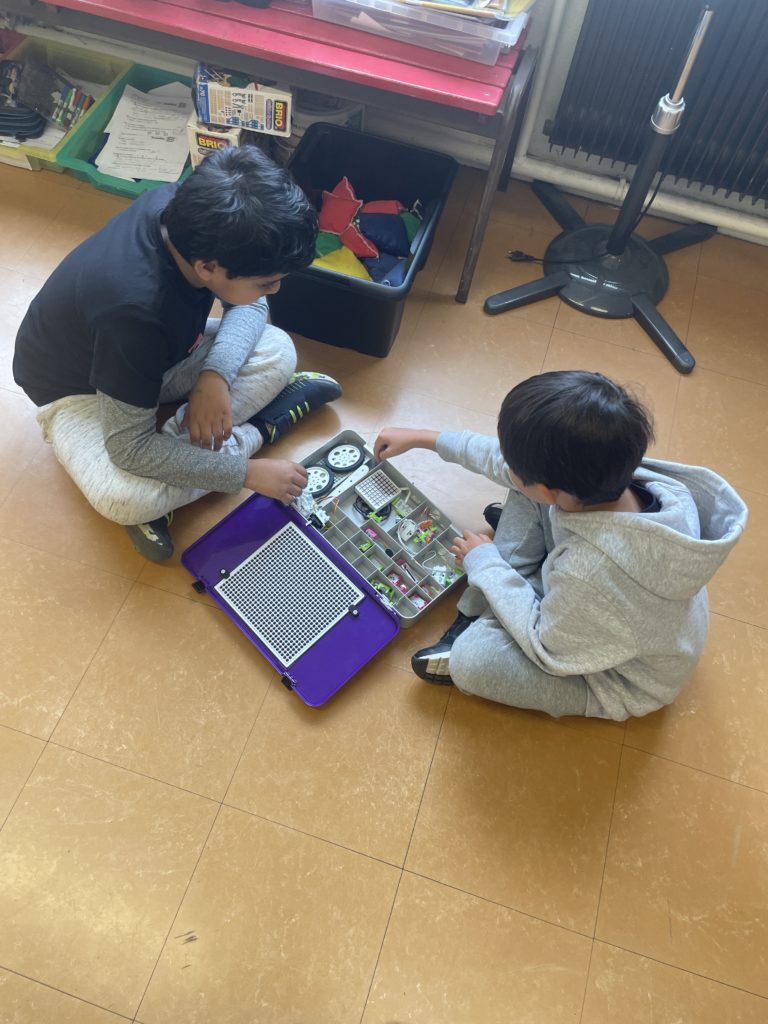 Students using components from a littleBits kit to build robots.