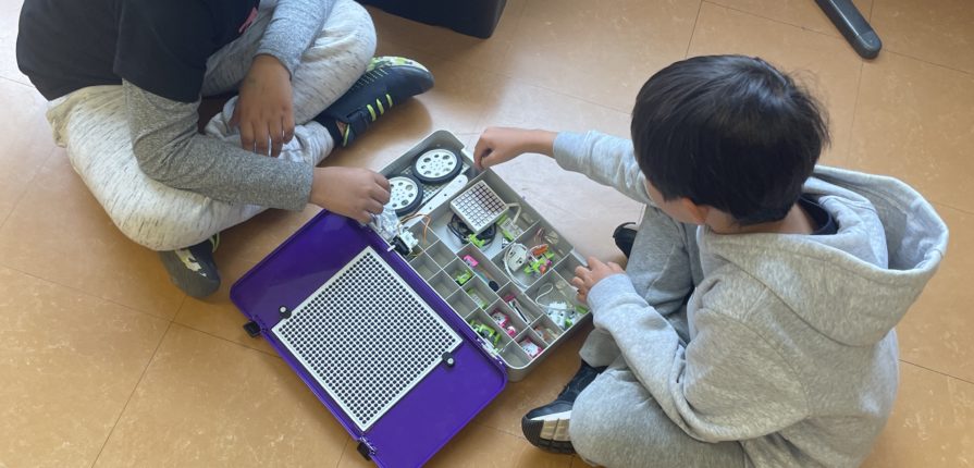 Students using components from a littleBits kit to build robots.