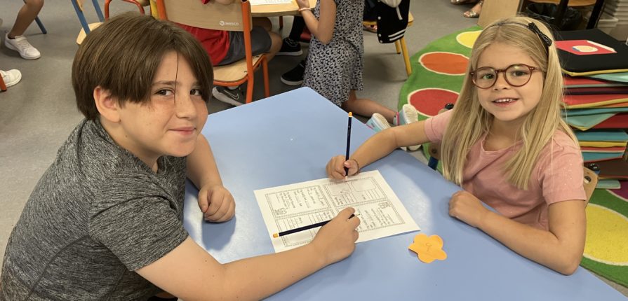 2 students sitting at a table in the library, working on a buddy activity