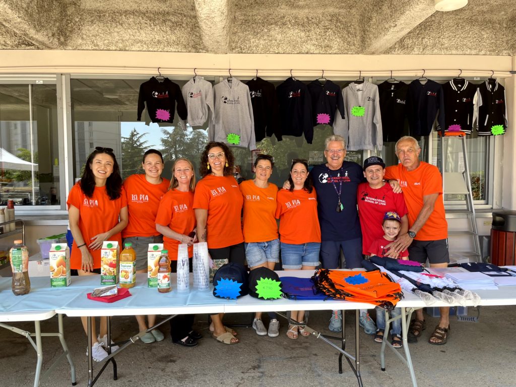 The members of the welcoming committee, dressed in ISL shirts, standing at a refreshment and merchandise table