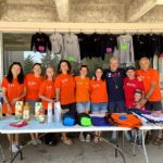 The members of the welcoming committee, dressed in ISL shirts, standing at a refreshment and merchandise table