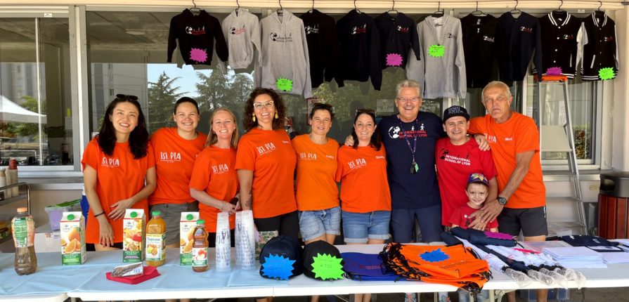 The members of the welcoming committee, dressed in ISL shirts, standing at a refreshment and merchandise table