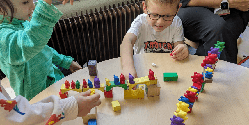 Kindergarten students building bridges with blocks and testing them with colourful teddy bear figures