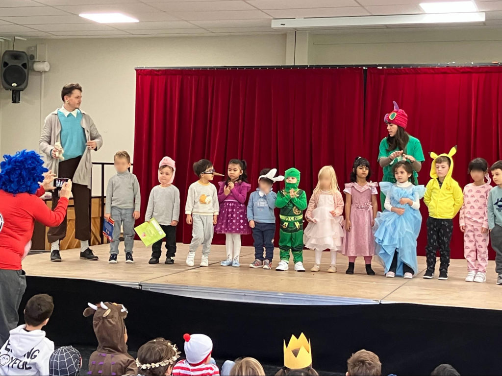 students standing on stage wearing costumes of their favourite book characters for book week