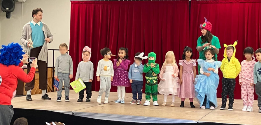 students standing on stage wearing costumes of their favourite book characters for book week