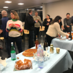 Parents and staff gathered in a room, tables set out with cakes and drinks