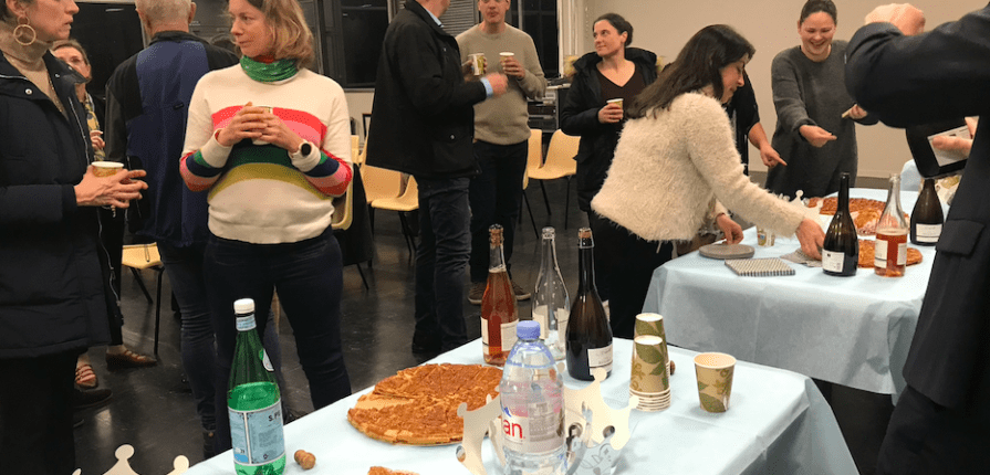 Parents and staff gathered in a room, tables set out with cakes and drinks