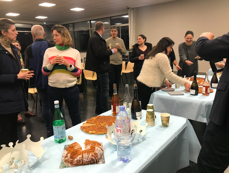 Parents and staff gathered in a room, tables set out with cakes and drinks