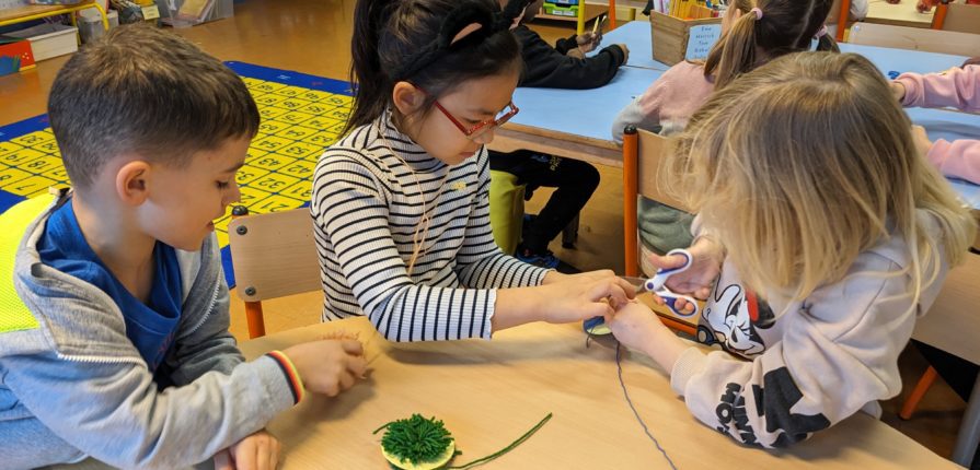 3 students working together to make a pom-pom with wool