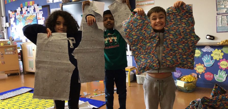 Students holding up the pairs of shorts that they made