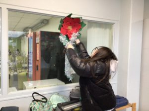 Студент снимает с окна красный бумажный цветок.