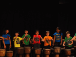 A group of grade 1 and 2 students perform on hand drums