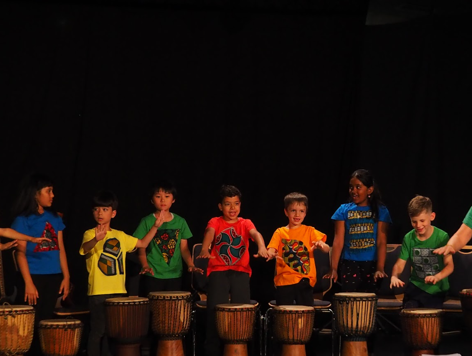 A group of grade 1 and 2 students perform on hand drums