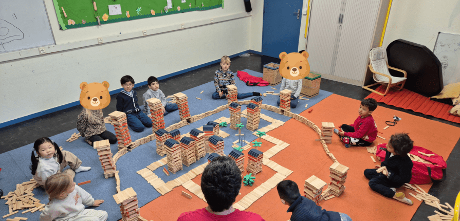 Students sitting on the carpet building Kapla towers
